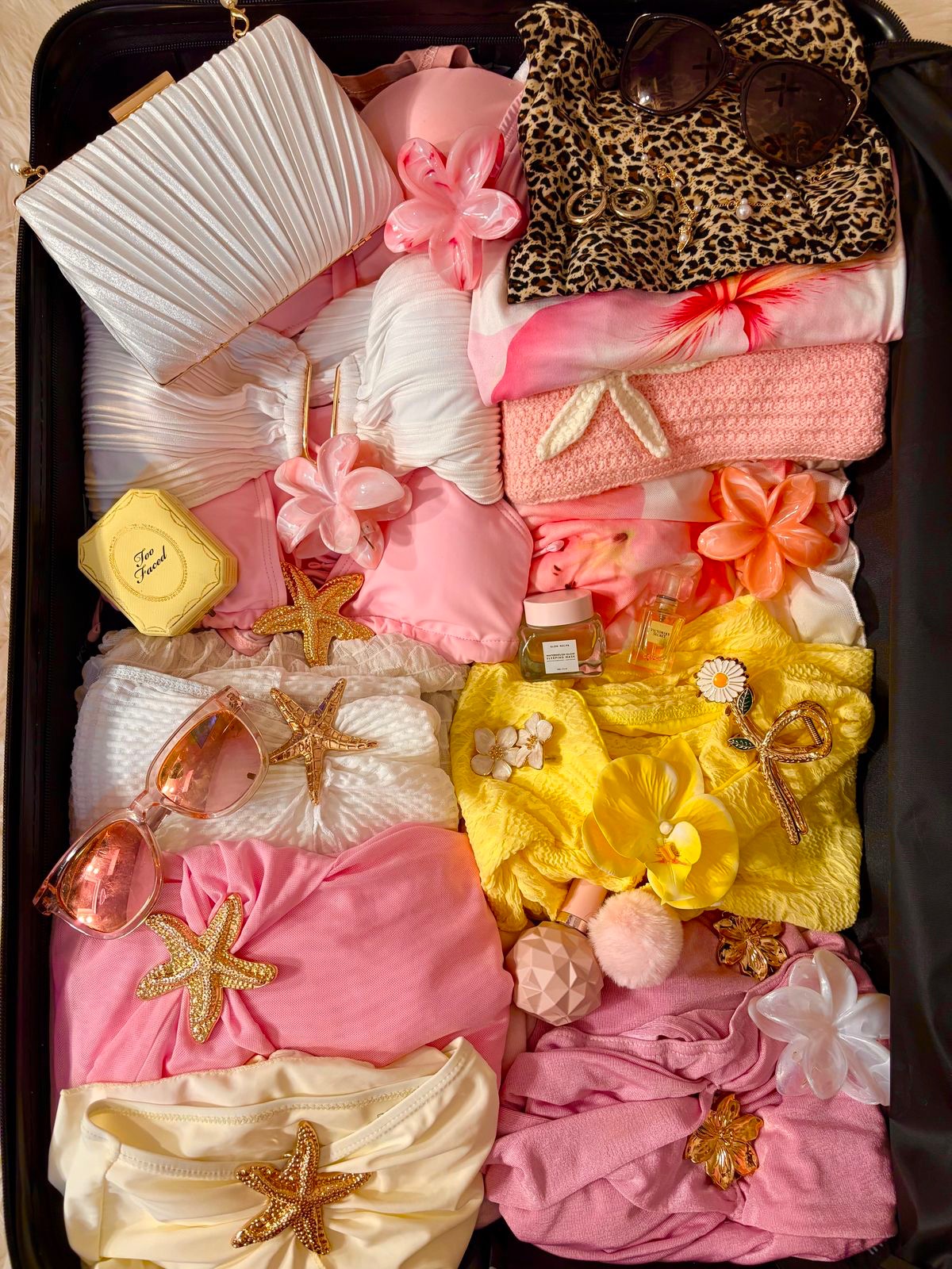 Organisation esthétique de maillots de bain texturés roses et jaunes, accompagnés d'accessoires tropicaux.