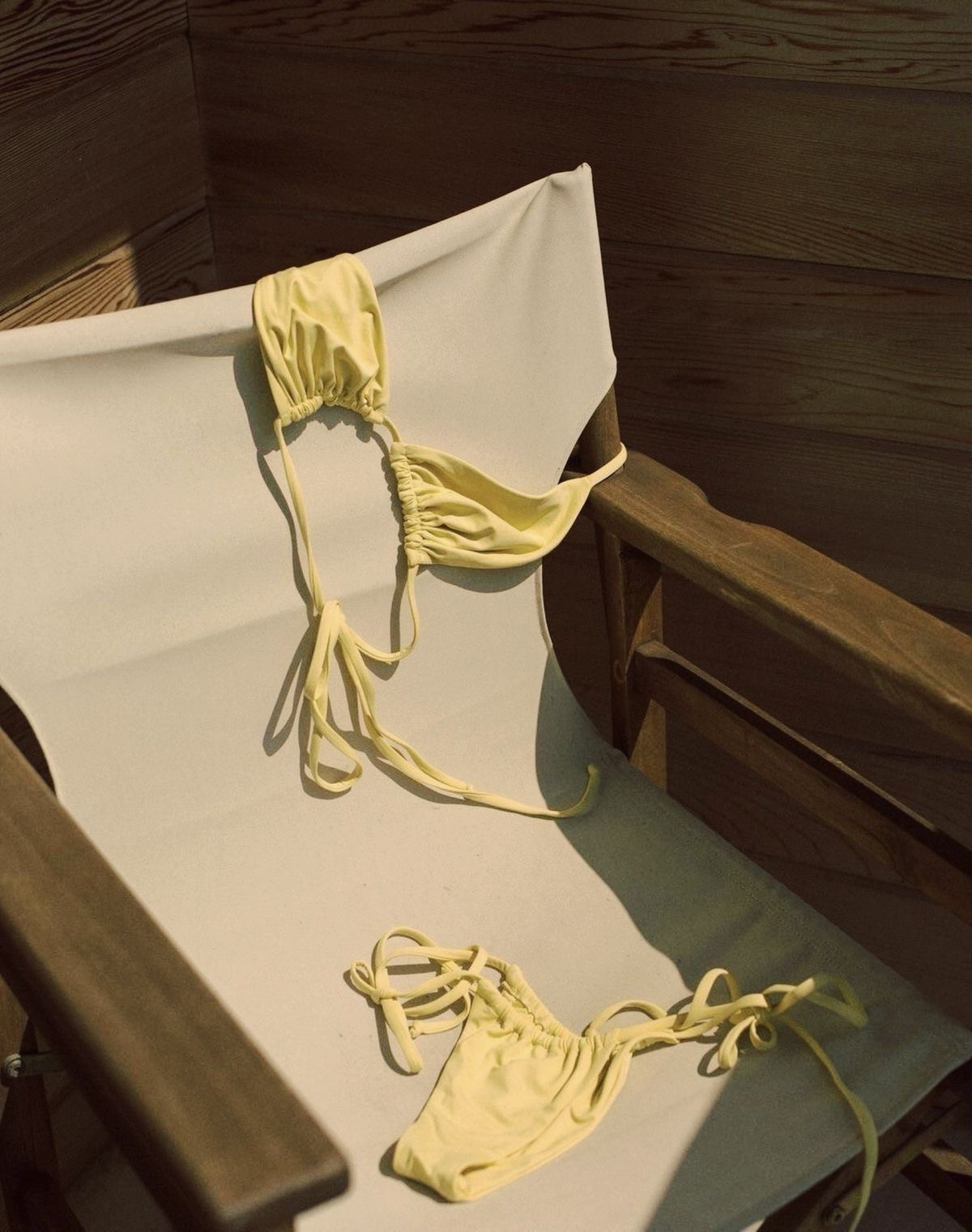 Un ensemble jaune pastel à bretelles nouées posé sur une chaise.